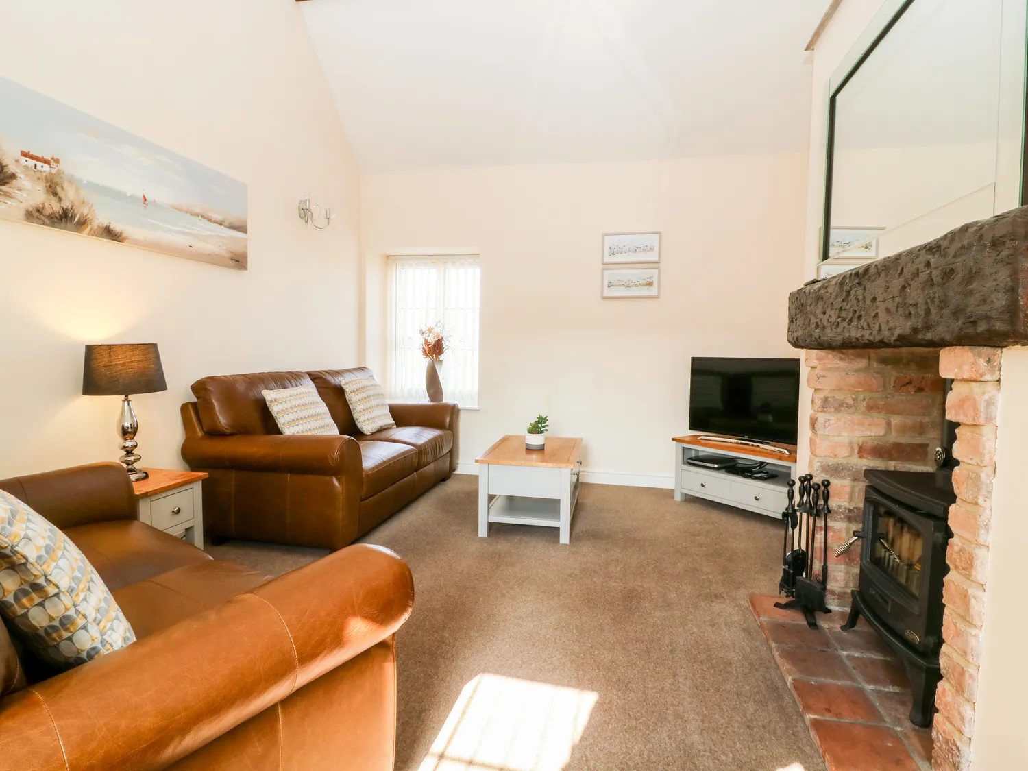 The sitting room with leather sofas and the brick fireplace