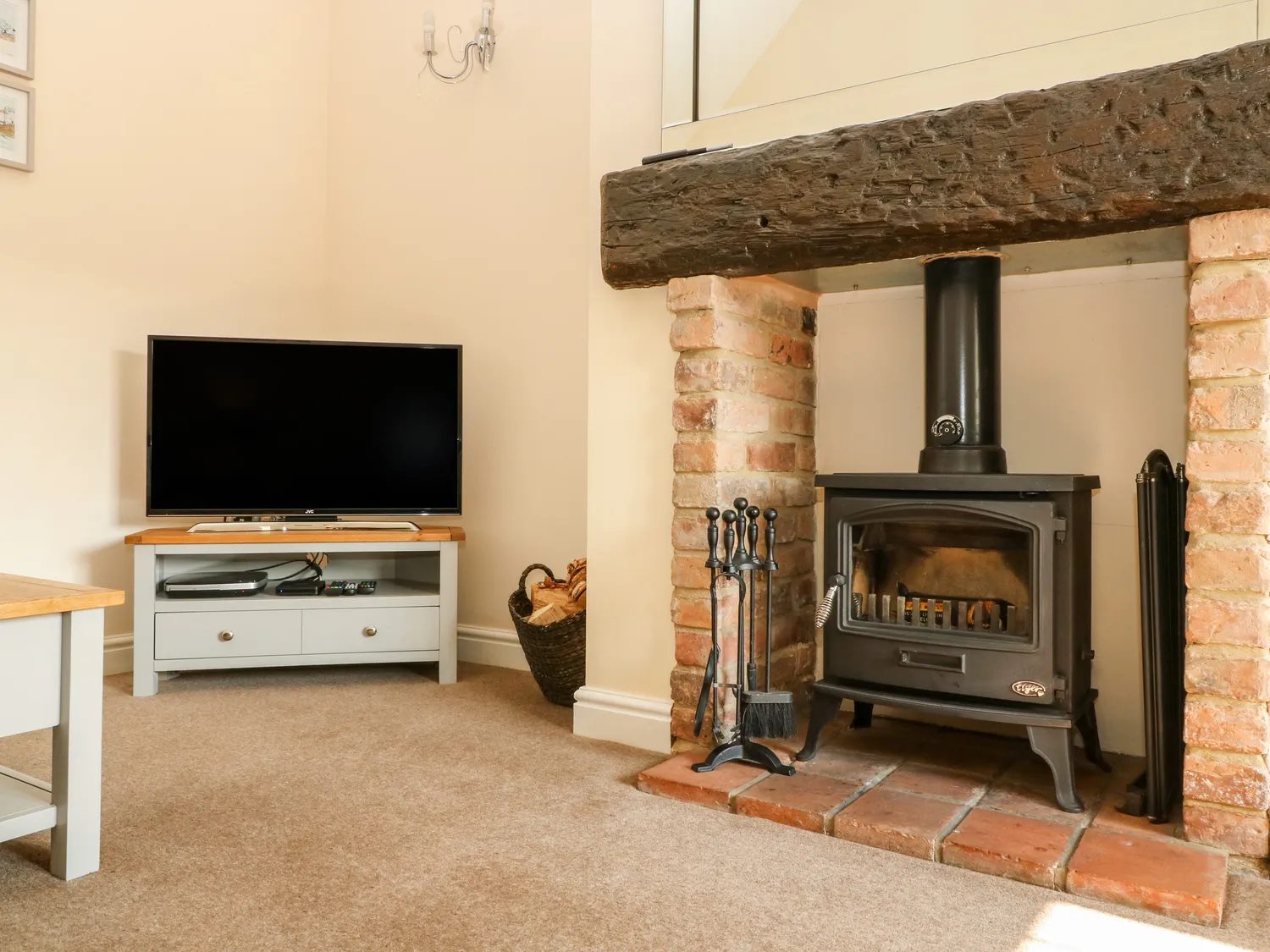 The log burner in its brick fireplace under an old timber beam